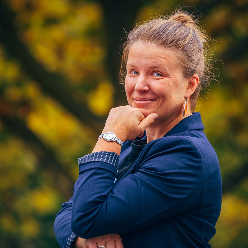 Portrait von Malgorzata Mikuck. Sie trägt ein blaues Oberteil und hat lange dunkelblonde Haare.